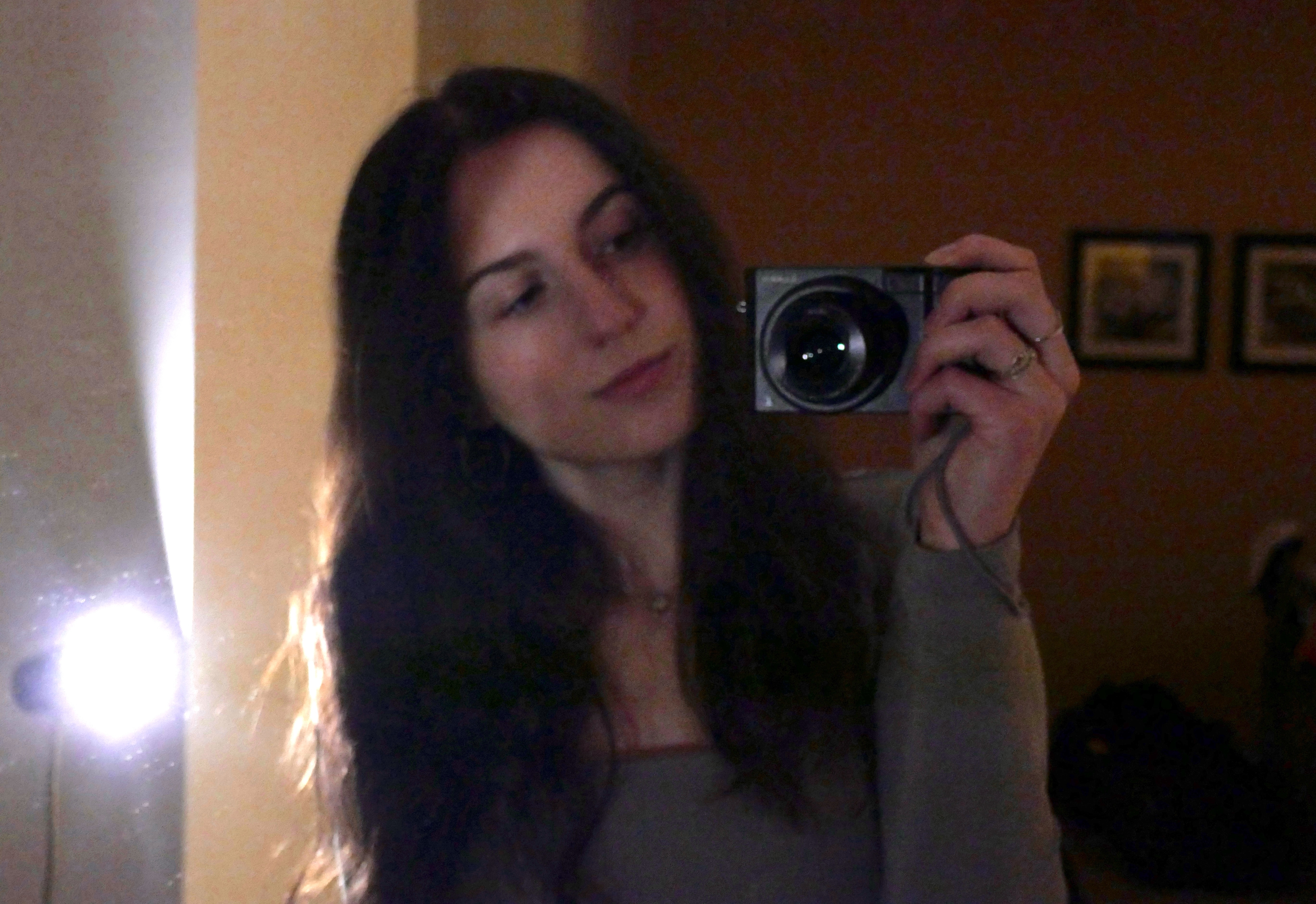 Diana Chalakova, holding a compact camera in a mirror