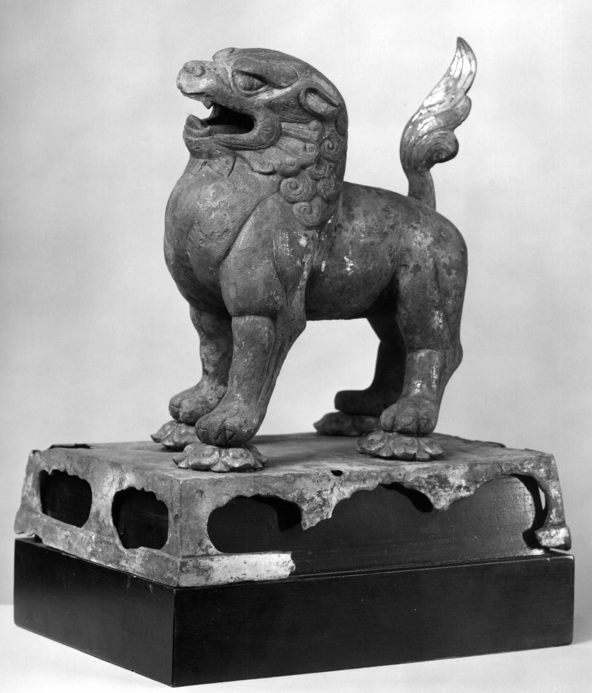The Standing Lion, Tang dynasty (618–907), 8th century — a stone guardian lion with open mouth and flame-shaped tail on a carved plinth