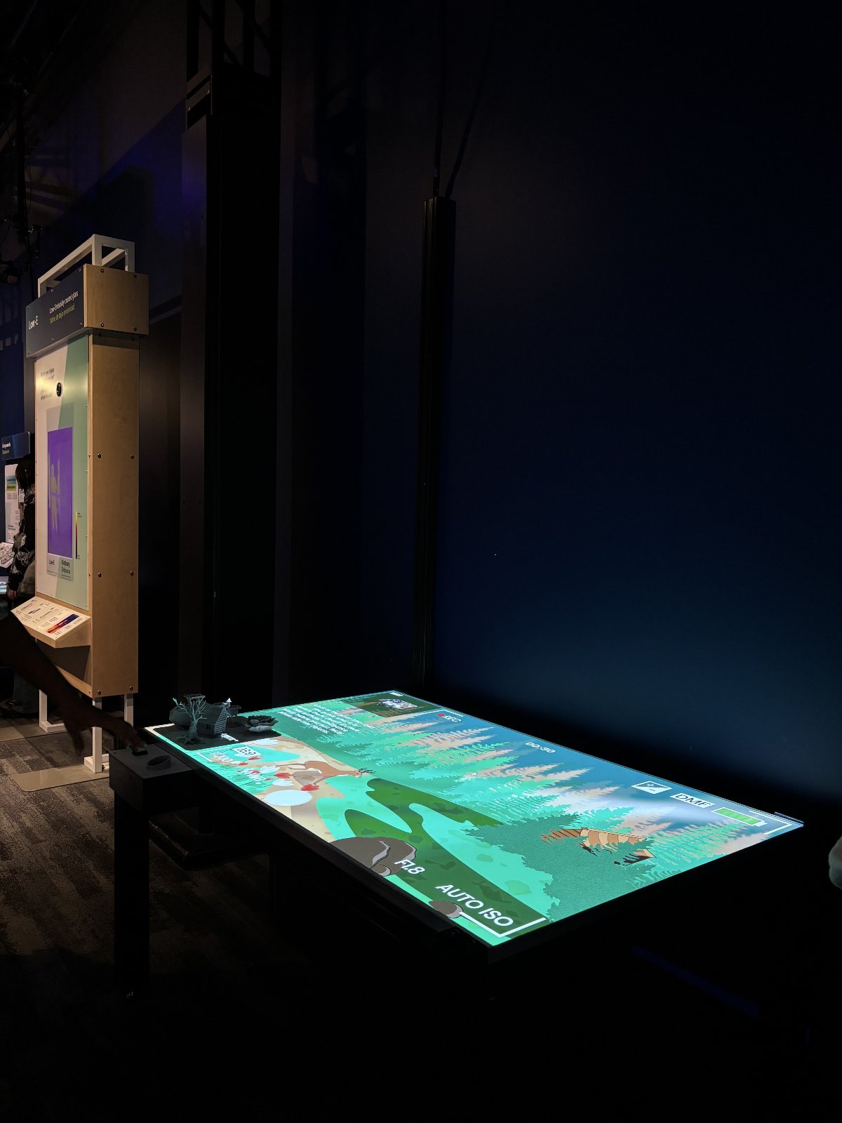 The FAST table installed on the Museum of Science floor — the forest scene glowing on the tabletop with 3D-printed objects along its edge