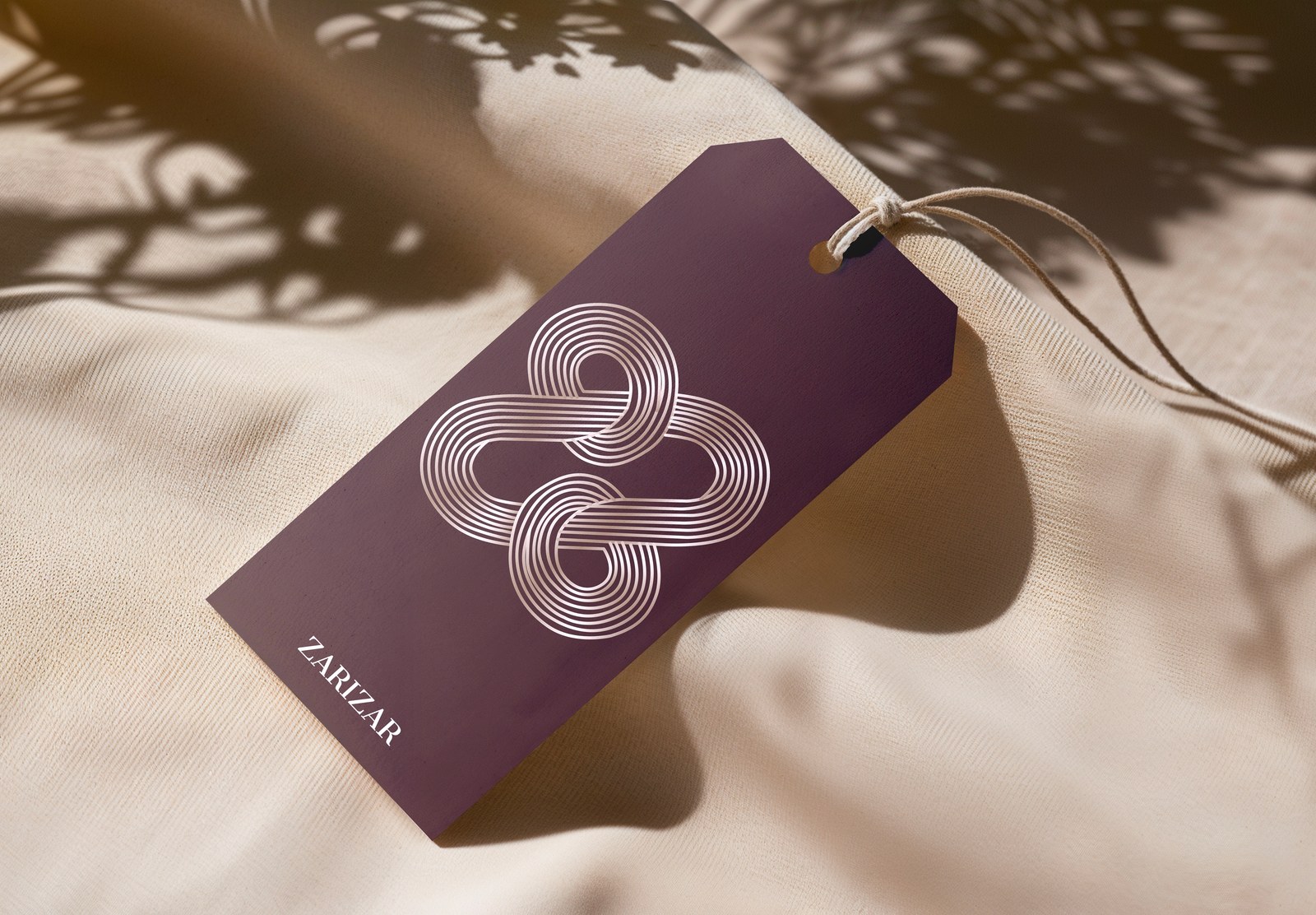 ZariZar product tag with a cream looping monogram on plum cardstock